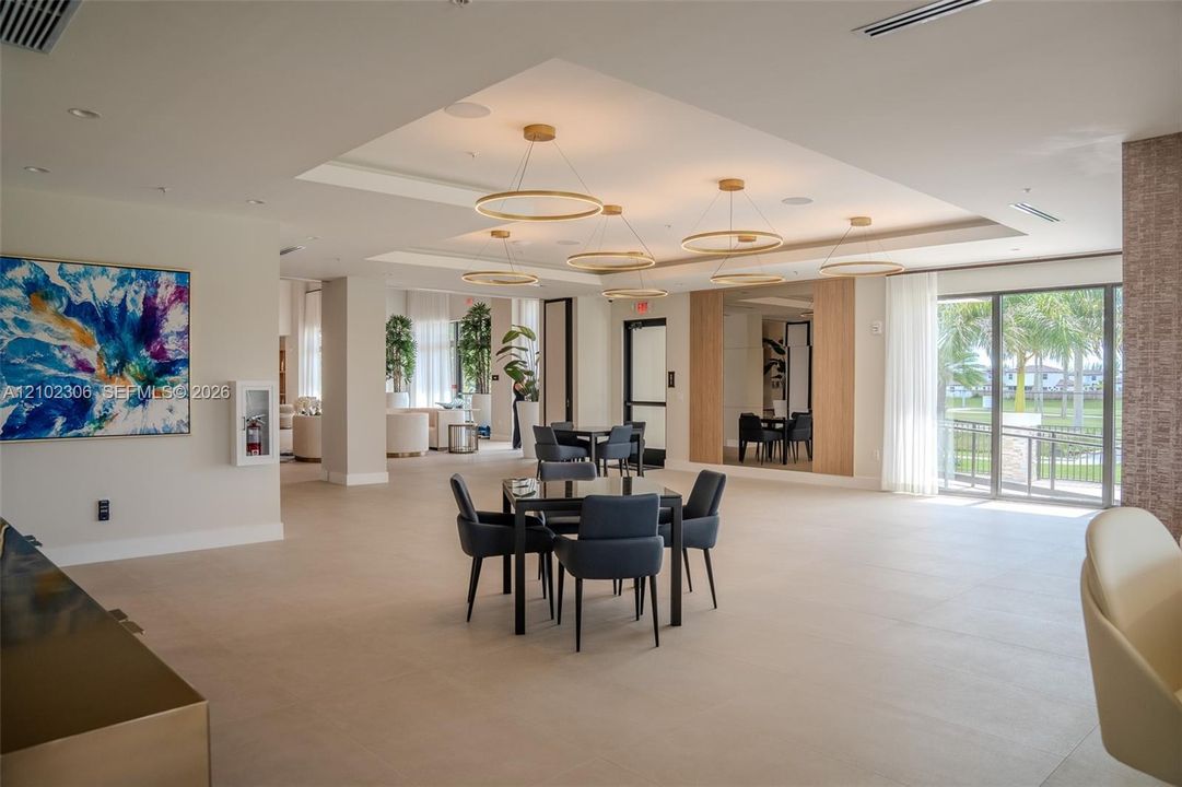 Open-concept floor plan featuring large-format tile flooring, recessed tray ceilings, custom circular pendant lighting, and full-height glass doors