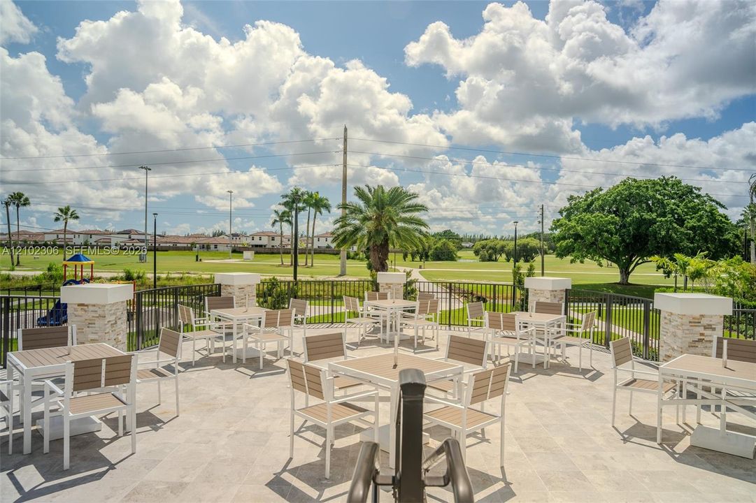 Expansive outdoor patio featuring light-toned stone tile flooring, stacked-stone pillar accents, and a metal perimeter railing