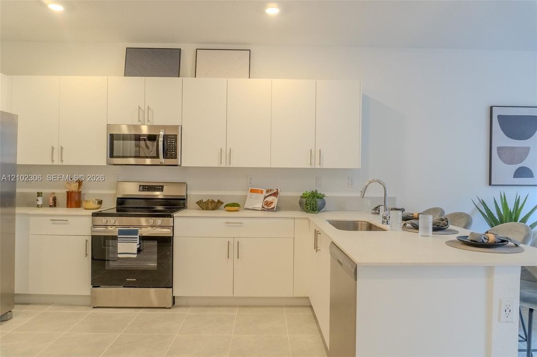 Kitchen featuring white cabinetry, solid-surface countertops, recessed lighting, and stainless steel appliances