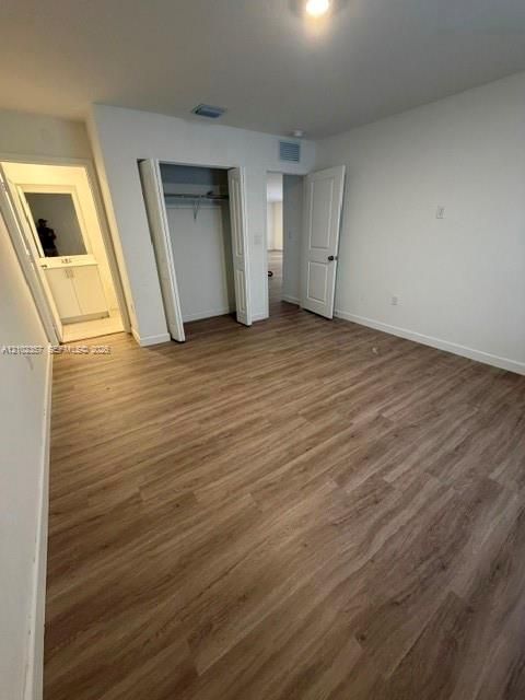 Wood-finish flooring, neutral wall tones, interior closet with shelving, and multi-panel interior door