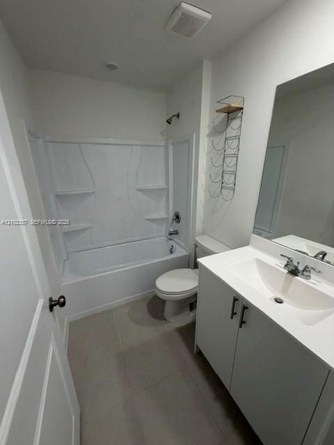 Bathroom featuring a white vanity cabinet with a stone countertop, integrated sink, large wall-mounted mirror, and a tub-shower combination with built-in shelving
