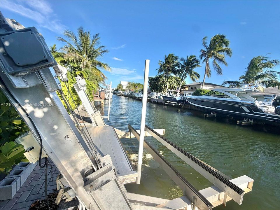 Waterfront property featuring a mechanical boat lift, concrete paver decking, and direct canal access