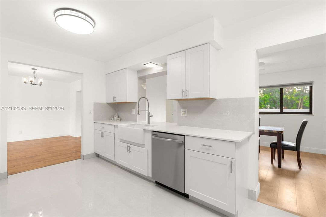 Kitchen featuring white shaker-style cabinetry, quartz countertops, a white farmhouse sink with a gooseneck faucet, stainless steel dishwasher, and polished tile flooring