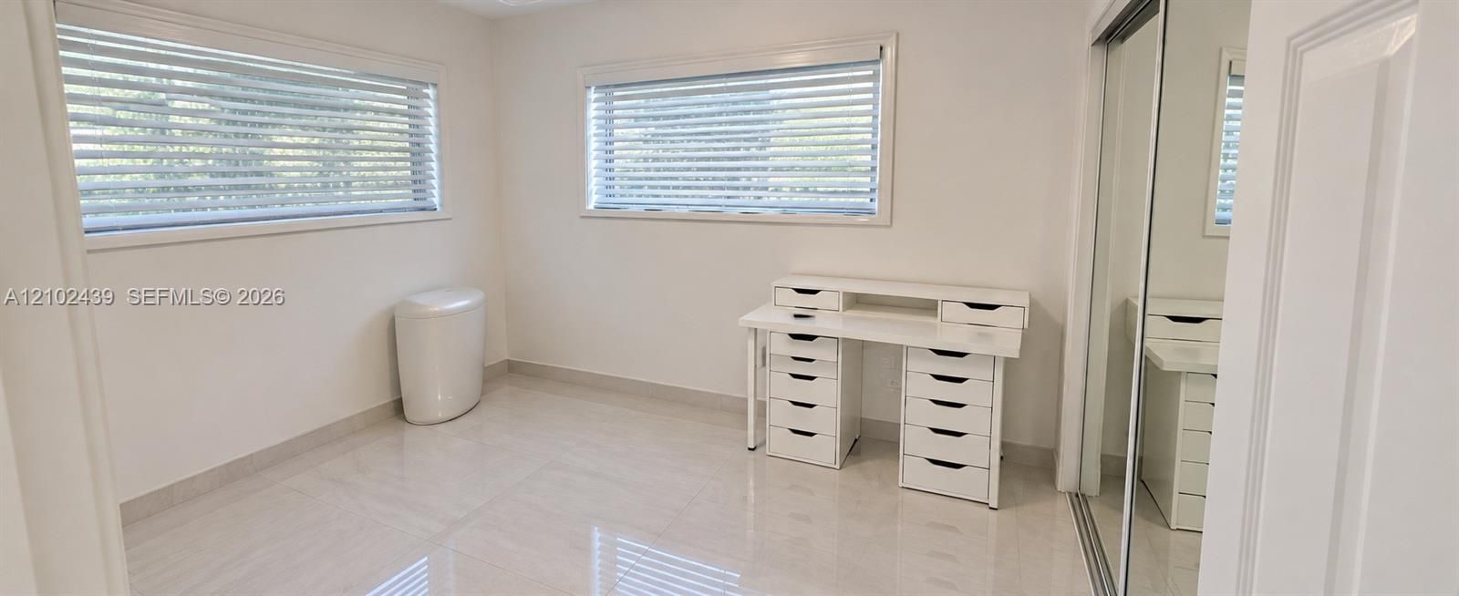 Tile flooring and two windows with blinds