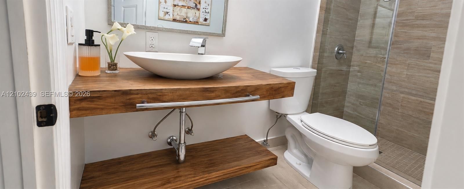 Floating wood vanity with integrated towel bar, vessel sink, and chrome faucet