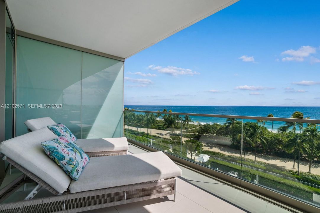 Covered terrace featuring large-format tile flooring, frosted glass privacy wall, and floor-to-ceiling glass panel railing with metal framing