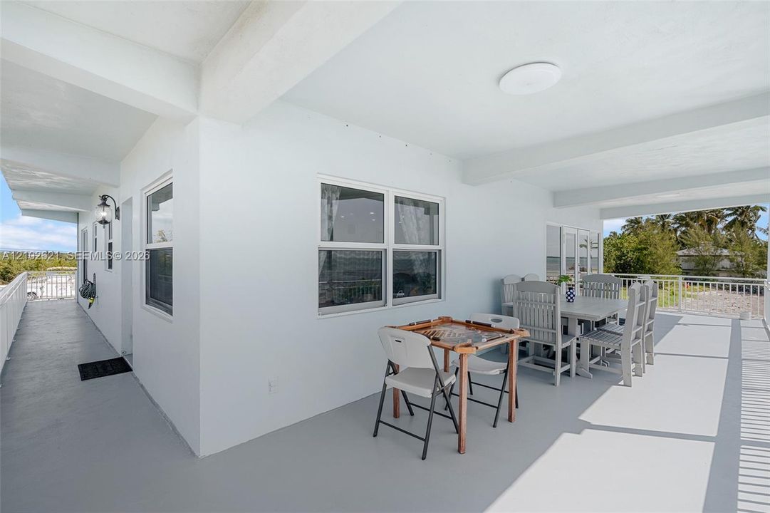 Expansive covered outdoor living area featuring multiple windows and a white railing