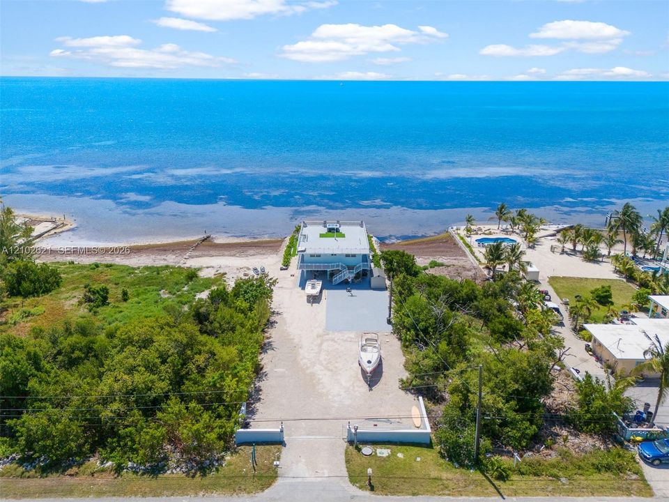 Coastal property with direct water frontage, multi-level structure, paved driveway, and established landscaping