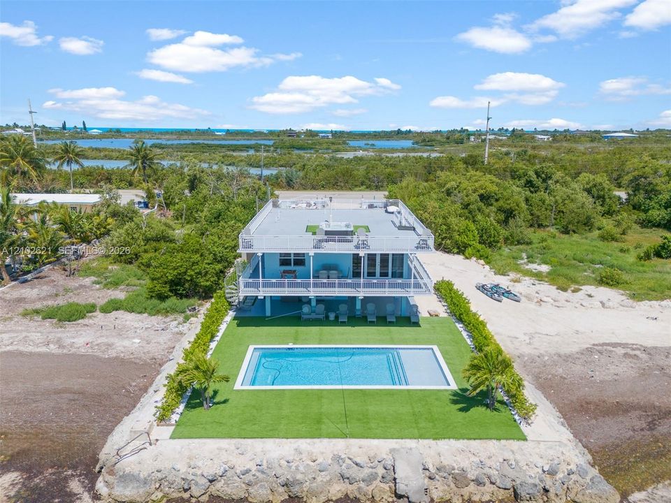 Two-story coastal residence featuring a rooftop deck, ground-level swimming pool, and a spiral staircase