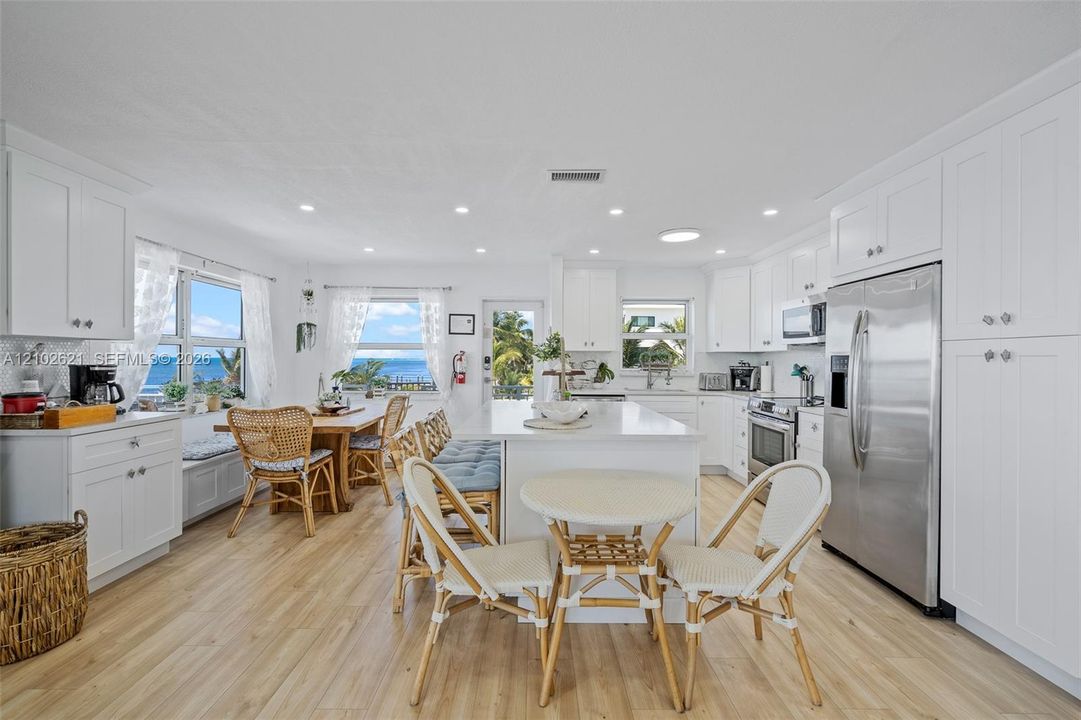 Open-concept kitchen and dining area featuring light-finish flooring, white cabinetry, a kitchen island, and stainless steel appliances