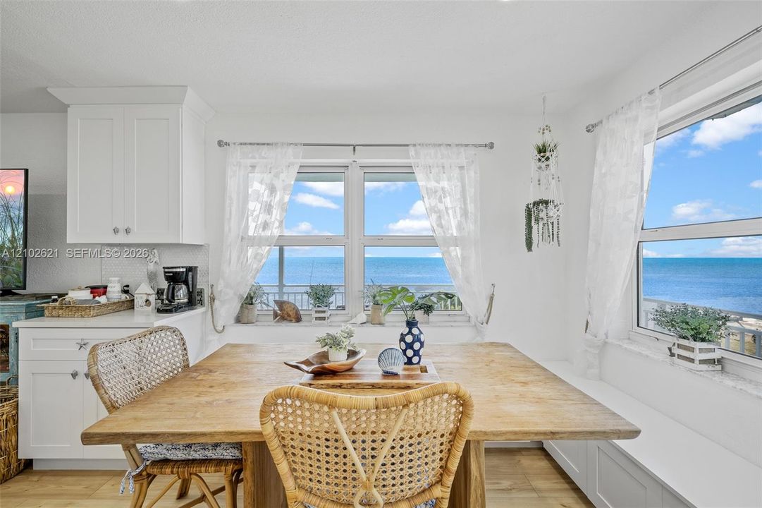 Built-in window bench seating with storage, white shaker-style cabinetry, and a white subway tile backsplash