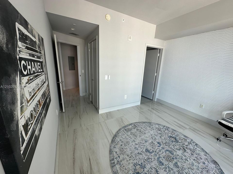 Polished stone-finish flooring with neutral veining, textured accent wall, and dual interior doorways