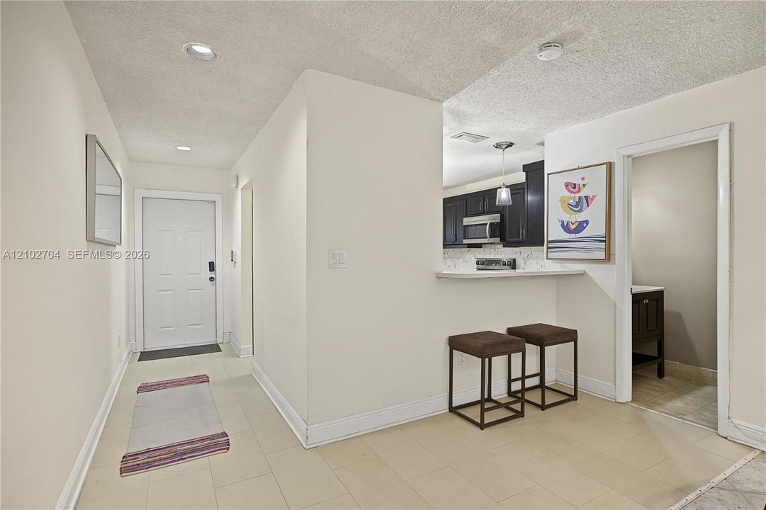 Entryway featuring neutral tile flooring,recessed lighting, and a breakfast bar with stone-finish countertops