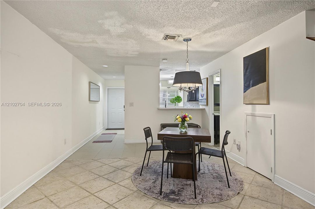 Interior space featuring large-format diagonal tile flooring, a pass-through opening to the kitchen, and a drum-style pendant light fixture