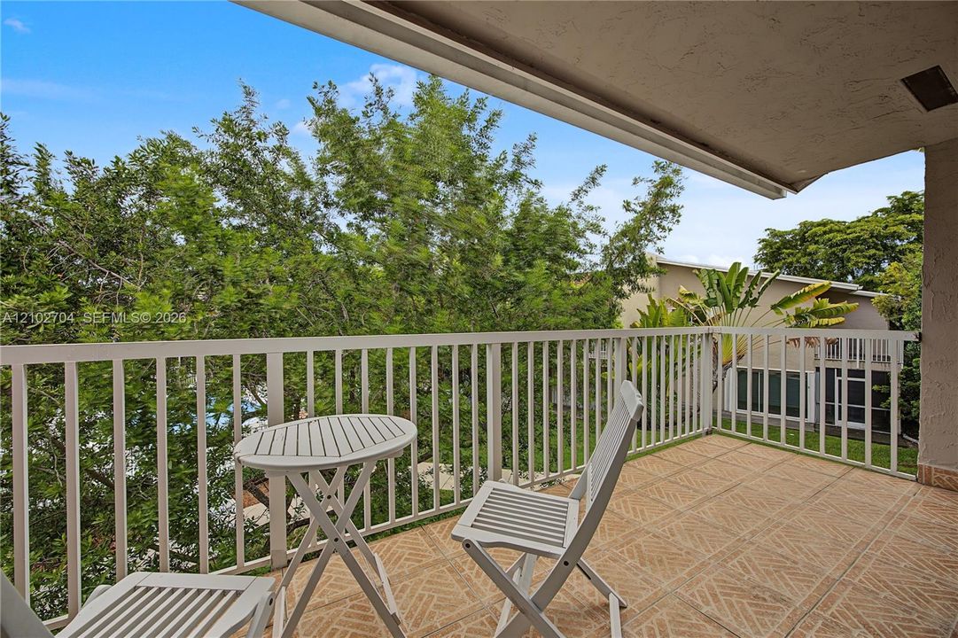 Covered balcony featuring patterned ceramic tile flooring and white metal railings