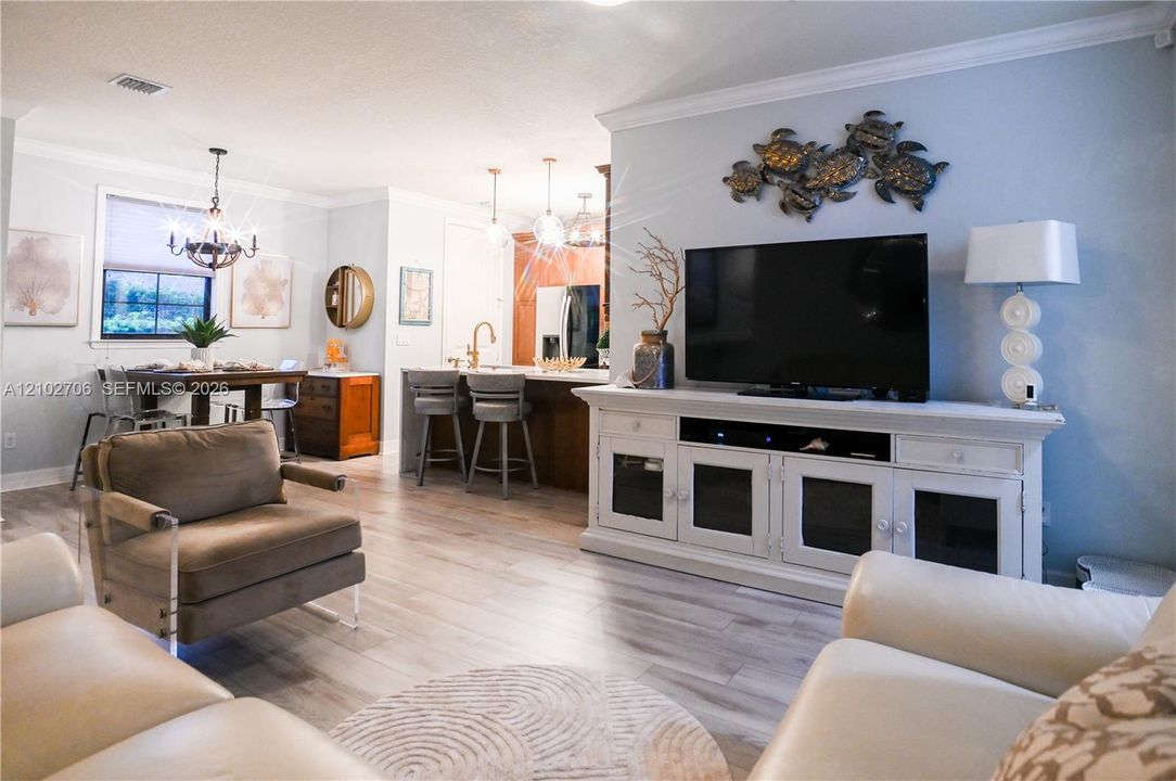 First floor primary. Neutral-toned room featuring wood-finish flooring, a ceiling fan with integrated lighting, and a window with blinds