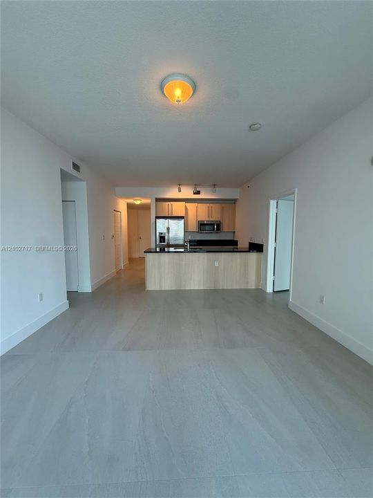 Open-concept interior featuring large-format tile flooring, flat-panel cabinetry, a kitchen island with stone-finish countertops, and stainless steel kitchen appliances