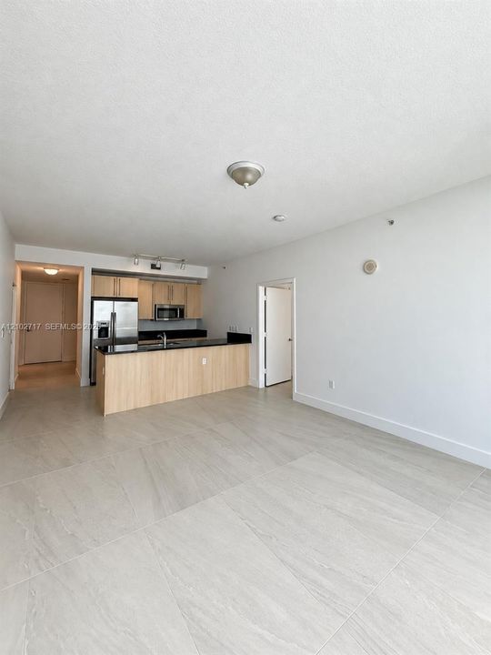 Large-format tile flooring, kitchen featuring wood-finish cabinetry, stone-surface countertops, and stainless steel appliances