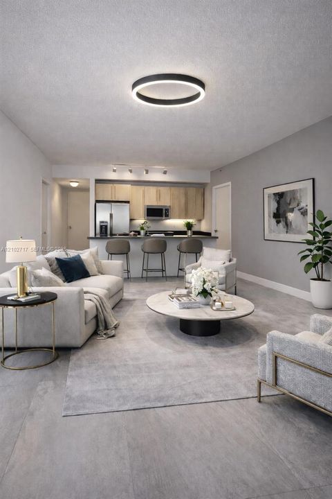 Open-concept floor plan featuring large-format tile flooring, a breakfast bar, wood-finish cabinetry, and a circular LED flush-mount light fixture