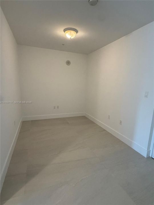 Interior space featuring neutral wall tones, large-format tile flooring, and a central flush-mount ceiling light fixture