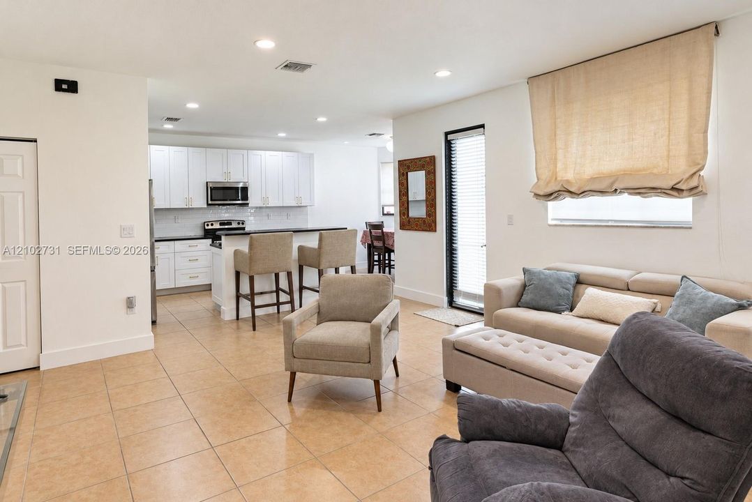 Kitchen featuring white shaker-style cabinetry, a breakfast bar, recessed lighting, and tile flooring