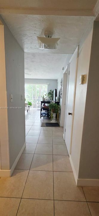Ceramic tile flooring, neutral wall tones, flush-mount ceiling light fixture, and interior doors