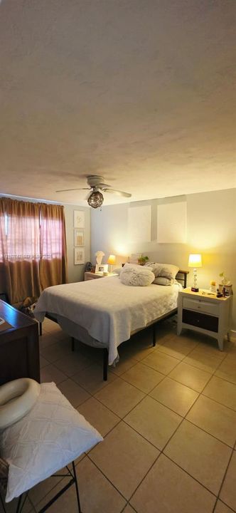 Neutral tile flooring, ceiling fan with integrated lighting, and window treatments
