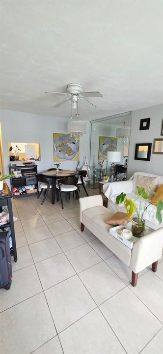 Ceramic tile flooring, mirrored wall accent, ceiling fan with integrated lighting, and pass-through wall opening