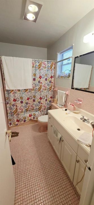 Bathroom featuring a vanity with integrated sink, rectangular mirror, ceiling-mounted light fixture, and tiled flooring