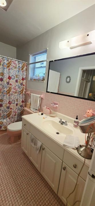 Bathroom featuring white cabinetry, integrated sink, large wall-mounted mirror, mosaic-tiled walls, and a multi-light fixture