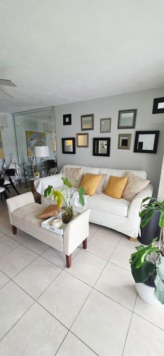 Living area featuring large-format ceramic tile flooring and a full-height mirrored wall panel