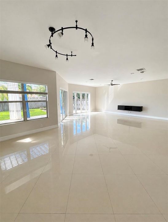 Open interior space featuring polished tile flooring, wall-mounted cabinetry, circular track lighting, and dual glass sliding doors