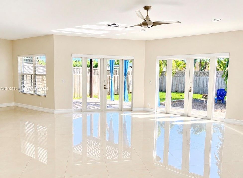 Polished tile flooring, recessed lighting, ceiling fan, and dual sets of glass-paned doors