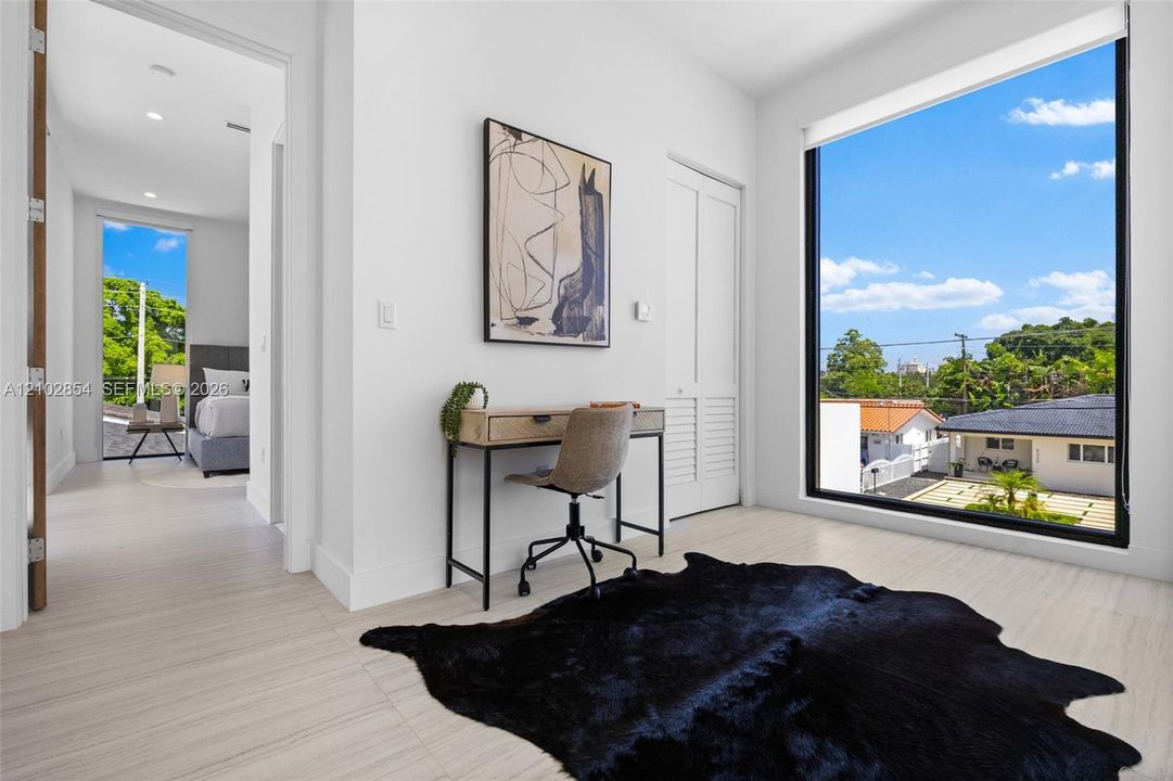 Large floor-to-ceiling windows, light-toned wood-finish flooring, and white louvered closet doors