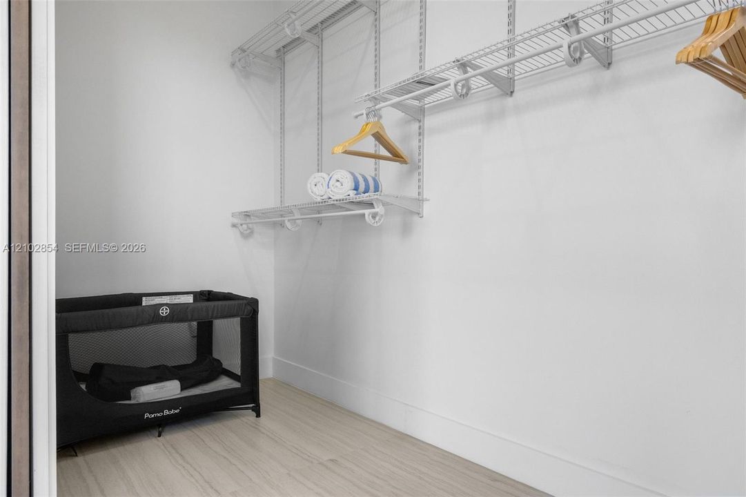 Walk-in storage space featuring wood-finish flooring and tiered white wire shelving
