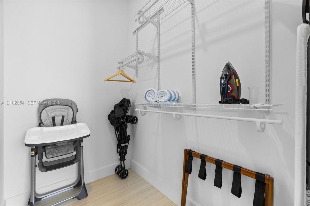 Storage area featuring white wire shelving units, dual hanging rods, and wood-finish flooring