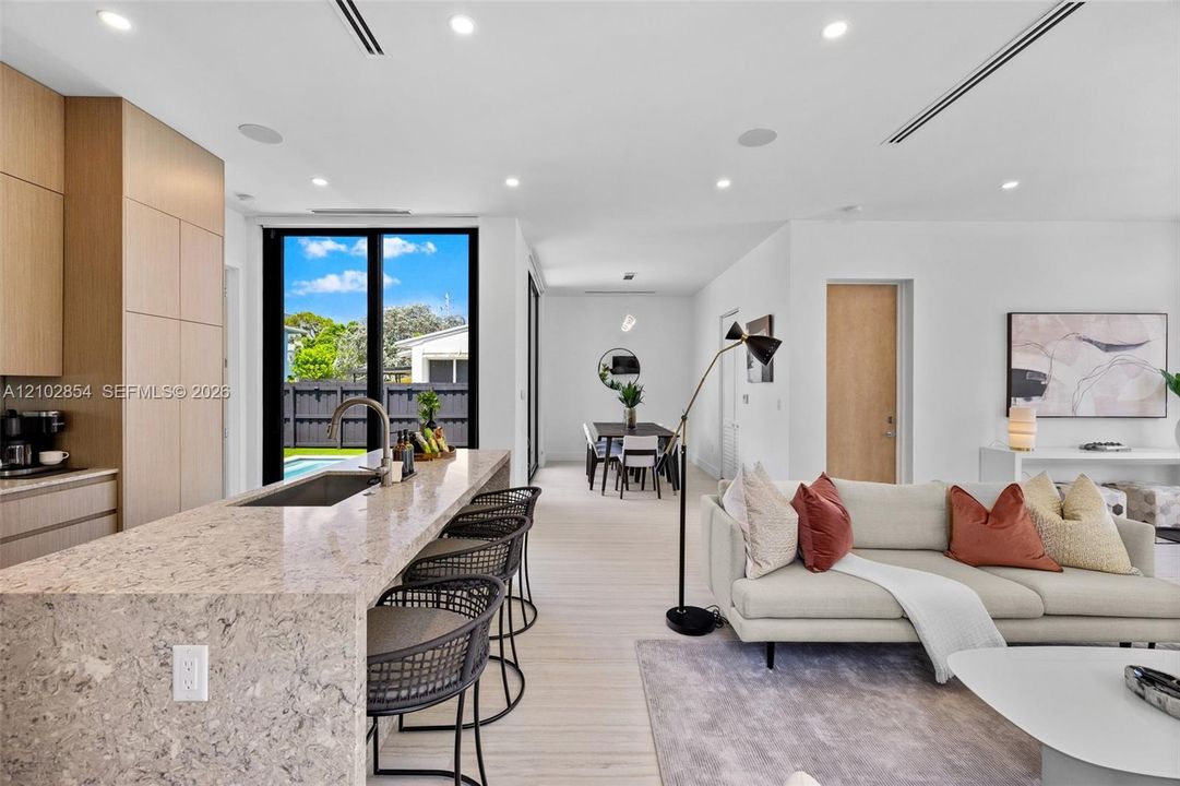 Kitchen featuring flat-panel wood cabinetry, stone-finish countertops, an undermount sink, recessed lighting, and floor-to-ceiling glass doors