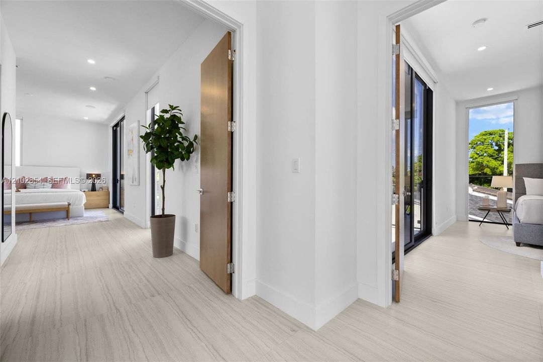 Interior space featuring wood-finish flooring, recessed lighting, solid wood doors with metallic hinges, and black-framed sliding glass doors