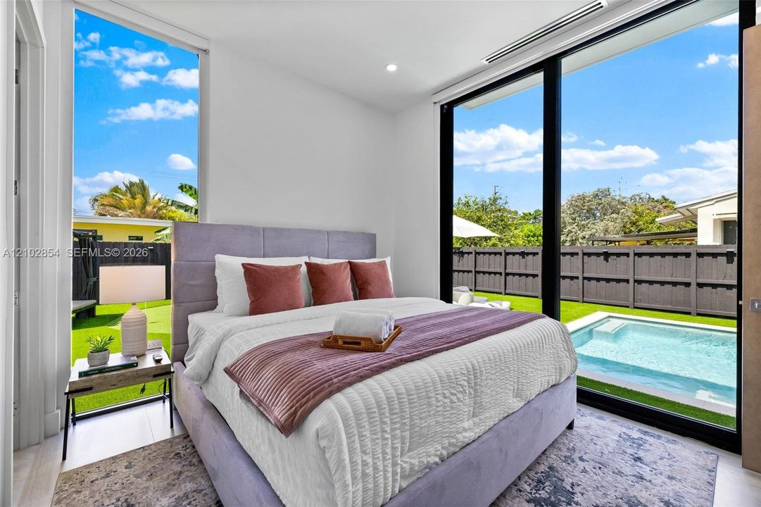 Floor-to-ceiling windows, sliding glass door, recessed ceiling lighting, and exterior access to a private pool and yard