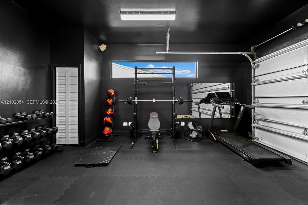 Multi-purpose space featuring matte black walls, a horizontal clerestory window, recessed overhead lighting, and a white paneled garage door