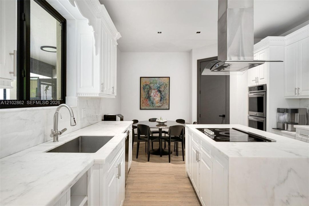 Kitchen featuring white cabinetry, stone countertops, stainless steel undermount sink, built-in double wall oven, and wood-finish flooring