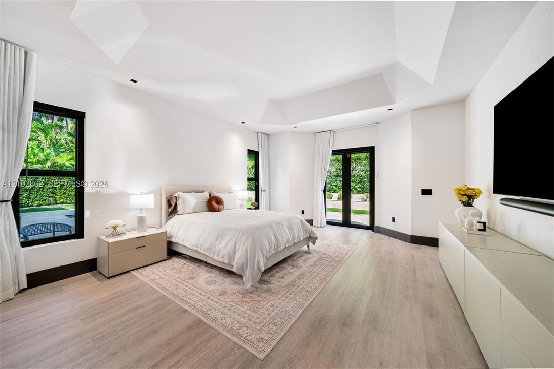 Vaulted ceiling featuring recessed lighting, wood-finish flooring, and black-framed windows with double-door exterior access