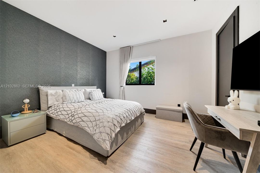 Textured charcoal accent wall featuring recessed ceiling lighting, light wood-finish flooring, and black window trim