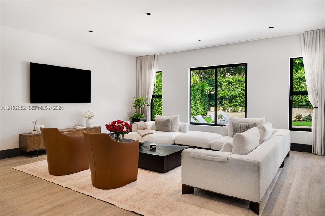 Living space featuring wood-finish flooring, recessed lighting, and large windows with black frames