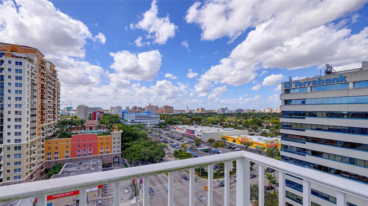 Elevated balcony with white metal railings overlooking an urban cityscape