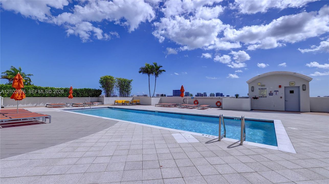 Rooftop swimming pool featuring a tiled deck, concrete perimeter wall, and built-in entry ladder