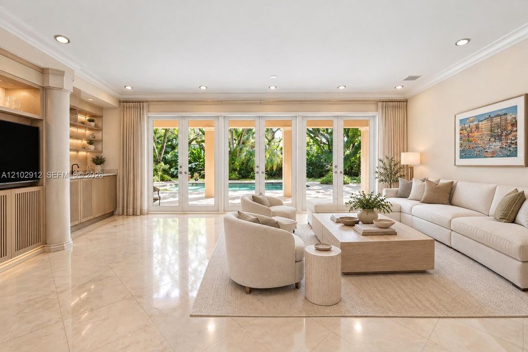 Polished tile flooring with recessed lighting, crown molding, and a built-in wet bar featuring back-lit shelving