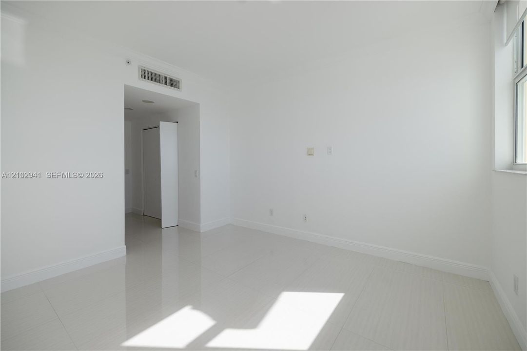 Interior space featuring polished tile flooring, neutral wall finishes, and a window with white casing