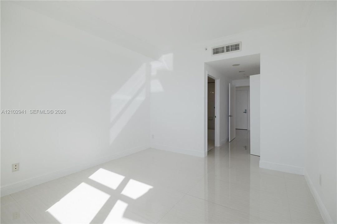Neutral-toned interior space featuring polished tile flooring, recessed ceiling lighting, and smooth-finish walls