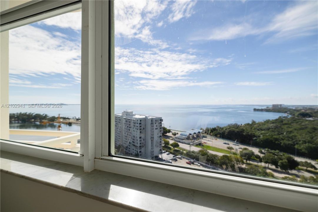 Expansive window featuring a polished stone sill and water horizon backdrop